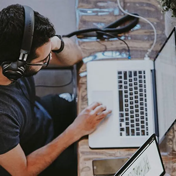 A man with a headset working on a laptop, seen from above