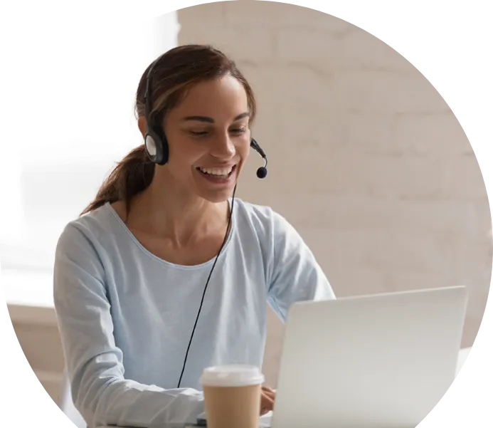 A smiling woman with a headset working at a laptop